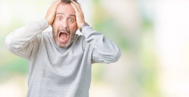 İzole arka planda bir sweatshirt giyen yakışıklı Orta Çağ kıdemli adam çılgın ve baş elleri ile korkuyor, korku ve açık ağız ile şok şaşırttı