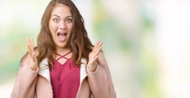 Artı boyutu genç kadın güzel üzerinde kış ceket giymiş deli kutluyor arka plan izole ve silah ile başarı için yükseltilmiş ve açık gözleri heyecanlı çığlık hayrete düşürdü. Kazanan kavramı