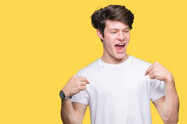 Yüzünde gülümseme ile kendinden emin görünüyorsun, kendini gururlu ve mutlu parmakları ile işaret izole arka plan üzerinde rahat beyaz t-shirt giyen genç yakışıklı adam.