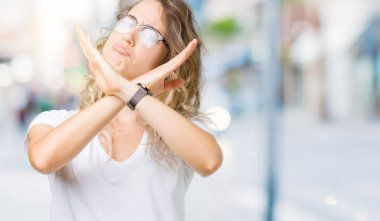 İzole arka plan ret ifade geçiş kollarına eksi işareti, kızgın surat yapıyor gözlüklü güzel sarışın genç kadın