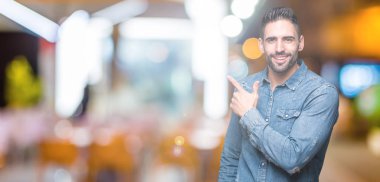 Yakışıklı delikanlı izole arka neşeli bir gülümseme ile el ve parmak kadar yan yüzünde mutlu ve doğal ifade ile işaret yüz üzerinden