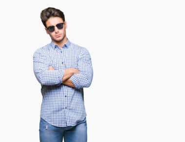 Genç yakışıklı adam izole arka plan şüpheci ve sinir, onaylamayan ifade yüz çapraz kolları üzerinde güneş gözlüğü takıyor. Negatif kişi.