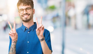 Zafer işareti yapıyor parmak gösterilen kamera seyir gülümseyen izole arka plan üzerinde gözlük takan yakışıklı delikanlı. İki numaralı.