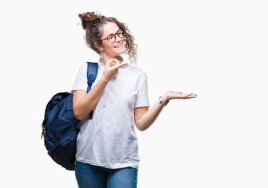 Sırt çantası ve kulaklık üzerinden hayran ve el ile sunulması ve parmak ile işaret ederken kameraya gülümseyen izole arka plan giyen genç esmer öğrenci kız.