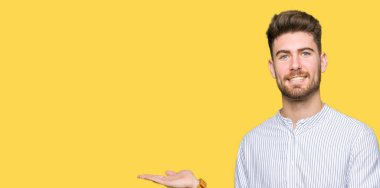 Hayret ve el ile sunulması ve parmak ile işaret ederken kameraya gülümseyen yakışıklı delikanlı.