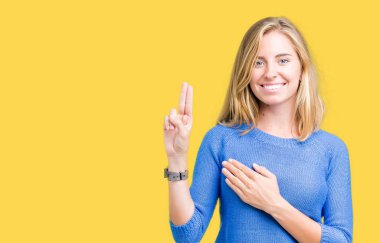 Mavi kazak izole üzerinde giyen güzel genç kadın arka plan Swearing göğüs ve parmaklar, el ile bir sadakat sözü yemin yapma