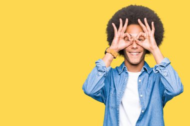Afrikalı-Amerikalı genç afro saçlı dilini, parmaklarının arasından baktığını yapışmasını dürbün gibi ok jest yapıyor. Deli ifade.