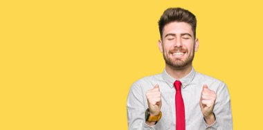 Genç yakışıklı iş adamı silah ile başarı için heyecanlı zafer kutluyor gülümseyen kaldırdı. Kazanan kavramı.