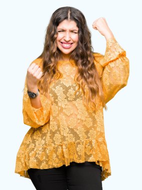 Gülümseyen ve başarı için çığlık sarı zarif elbise çok mutlu ve heyecanlı kaldırdı, silah ile kazanan jest yapıyor giyen genç güzel kadın. Kutlama kavramı.