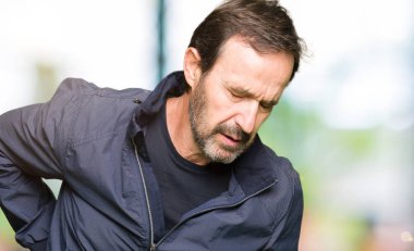 Orta yaş yakışıklı adam bir ceket giyiyor sırt ağrısı muzdarip, el ile geri dokunmadan, kas ağrısı