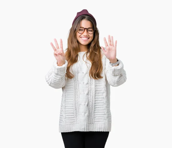 年轻美丽的黑发嬉皮士妇女戴着眼镜和冬天的帽子在孤立的背景显示和手指指向 同时微笑着自信和快乐 — 图库照片