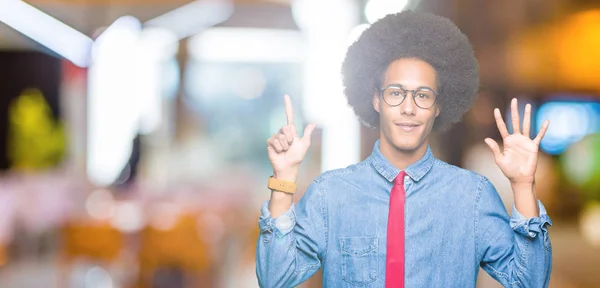 アフリカ系アメリカ人のビジネスマンで アフロの髪をしてメガネをかけ 赤いネクタイを見せて指で指さし 自信を持って笑顔で7番 — ストック写真