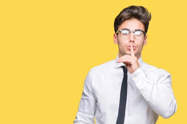 Young business man wearing glasses over isolated background asking to be quiet with finger on lips. Silence and secret concept.