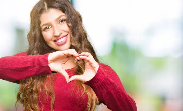 年轻美丽的女人穿着红色毛衣微笑着在爱中 用手显示心脏的象征和形状 浪漫的概念 — 图库照片