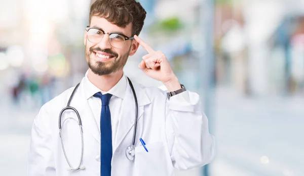 Junger Arzt Krankenhausmantel Über Isoliertem Hintergrund Lächelnd Mit Einem Finger — Stockfoto