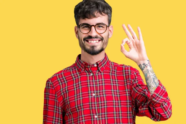 年轻英俊的男人戴着眼镜在孤立的背景微笑积极做确定的迹象与手和手指 成功的表达 — 图库照片