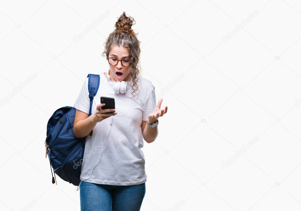 Young brunette student girl wearing backpack, headphones and smartphone over isolated background very happy and excited, winner expression celebrating victory screaming with big smile and raised hands