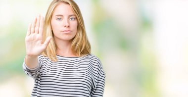 Giyen güzel genç kadın kazak elin avuç durağı şarkı yapıyor izole arka plan üzerinde çizgili. Negatif ve ciddi bir jest yüz ifadesiyle uyarı.