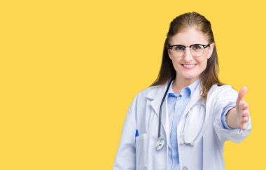 Orta yaş olgun doktor kadın üzerinde tıbbi bir palto giyiyor arka plan dostu sunan karşılıklı tebrik ve davet edici gülümseyen izole. Başarılı iş.