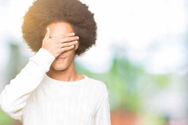 Afrikalı-Amerikalı genç afro saçlı kış kazak gülümsüyor ve gözleri sürpriz için kapsayan yüz el ile gülüyor. Kör kavramı.