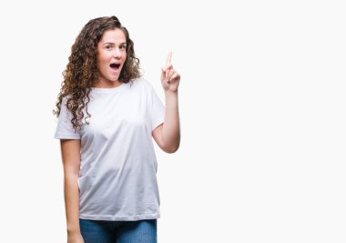 Güzel esmer kıvırcık saçlı Genç kız başarılı fikirle izole arka plan üzerinde işaret parmağı rahat t-shirt giyiyor. Çıktıktan ve mutlu. Bir numara.