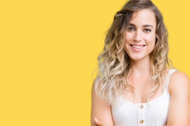 Genç güzel sarışın kadın izole arka plan mutlu yüz çapraz silah kameraya bakarak ile gülümseyen yüzünden. Olumlu bir kişi.