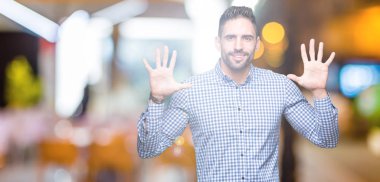 Yakışıklı delikanlı gösterilen ve parmakları ile işaret izole arka plan üzerinde kendinden emin ve mutlu gülümseyerek süre on numara.