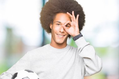 Mutlu yüz el parmaklarının arasından seyir göz üzerinde ok işaretiyle yapıyor gülümseyen ile futbol futbol topu tutan afro saçlı genç Afro-Amerikan adam