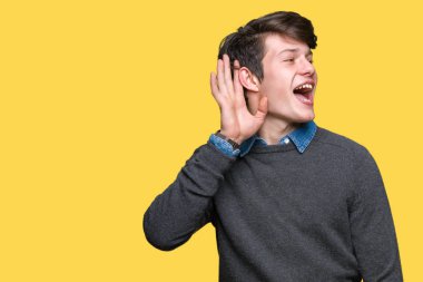 Genç yakışıklı zarif adam bir işitme söylenti ya da dedikodu için dinleme kulak üzerinde el ile gülümseyen izole arka plan üzerinde. Sağırlık kavramı.
