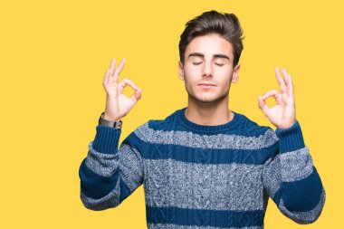 Yakışıklı delikanlı izole arka plan üzerinde dinlenmek ve gülümseyen gözlerle parmak ile meditasyon jest yapıyor kapalı. Yoga kavramı.