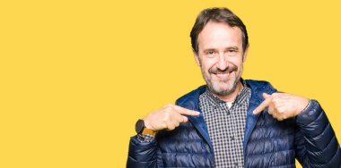 Yüzünde gülümseme ile kendinden emin görünüyorsun, kendini gururlu ve mutlu parmakları ile işaret kış ceket giyen orta yaş yakışıklı adam.