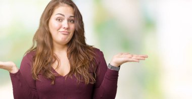 Güzel ve çekici artı boyutu üzerinde bir elbise giyen genç kadın arka plan clueless ve şaşkın bir ifadeyle kollar ve eller kaldırdı izole. Şüphe kavramı.