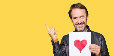 Kağıt kırmızı kalp ile çok mutlu el ve parmak ile tarafına işaret tutan yakışıklı orta yaş erkek