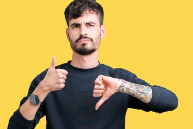 Yakışıklı delikanlı izole arka plan yapmaya başparmak yukarı ve aşağı, anlaşmazlık ve anlaşma ifade üzerinde. Deli çatışma