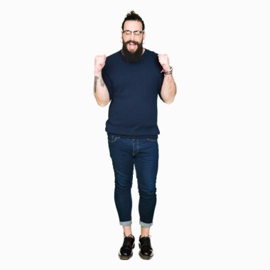 Uzun saç ve sakal silah ile başarı için heyecanlı gözlüklü genç hipster adamla zafer kutluyor gülümseyen kaldırdı. Kazanan kavramı.