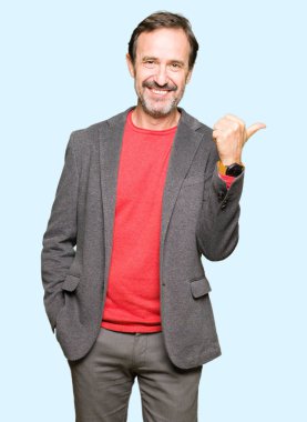 Orta yaş yakışıklı iş adam mutlu yüz görünümlü ve başparmak yukarı ile yan işaret gülümseyen.