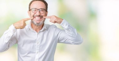 Yakışıklı orta yaş zarif üst düzey iş adamı kendine güvenen gösterilen ve işaret parmakları diş ve ağız ile gülümseyen izole arka plan üzerinde gözlük takıyorum. Sağlık kavramı.