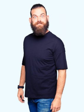 Komik surat ile rahat t-shirt şişirme yanakları giyen genç sarışın adam. Ağız ile hava, deli ifade şişirilmiş.