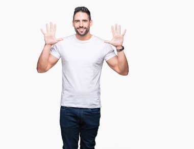 Gösterilen ve parmakları ile işaret izole arka plan üzerinde rahat beyaz t-shirt giyen genç adam kendinden emin ve mutlu gülümseyerek süre on numara.