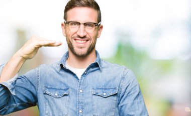 Gözlük giyen yakışıklı adam büyük ve büyük boyutlu işareti gösteren eller ile işaret, ölçü sembolü. Kameraya bakarak gülümsüyor. Ölçme konsepti.