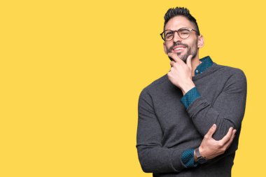 Emin çapraz kollar ve çeneme kaldırdı el ile gülümseme ile kameraya bakarak izole arka plan üzerinde gözlük takan yakışıklı delikanlı. Pozitif düşünce.