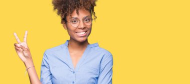 Güzel genç Afro-Amerikan iş kadını mutlu yüz zafer işareti yaparken kameraya göz kırpıyor ile gülümseyen izole arka plan üzerinde. İki numaralı.