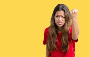 Öfkeli ve sinirli sinirli ve öfke ile bağırarak süre öfkeli yumruk yükselterek izole arka plan üzerinde kırmızı t-shirt giyen genç güzel esmer kadın. Öfke ve agresif kavramı.