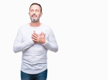 Orta yaş ağarmış komuta sizde ile gülümseyen izole arka plan üzerinde beyaz t-shirt giyen kapalı gözler ve yüzünde minnettar jest ile göğüs üzerinde eller. Sağlık kavramı.