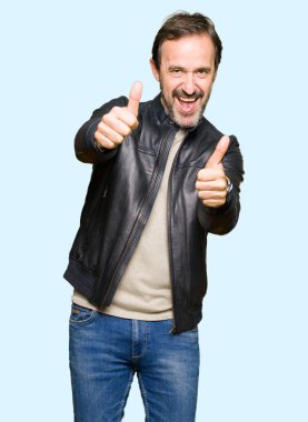 Siyah deri ceket onaylama giyen orta yaş yakışıklı adam el ile pozitif jest yapıyor gülümseyen ve başarı için mutlu yaşasın. Kamera, kazanan jest arıyorsunuz.