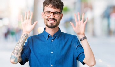 Gösterilen arka plan üzerinde gözlük takan genç yakışıklı adam izole ve parmakları ile işaret kendinden emin ve mutlu gülümseyerek süre on numara.