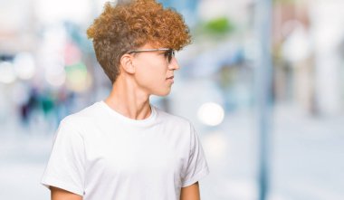 Yakışıklı genç afro saçlı uzak tarafına yüzünde, doğal ifade gülümseme ile seyir güneş gözlüğü takıyor. Kendine güvenen gülüyor.