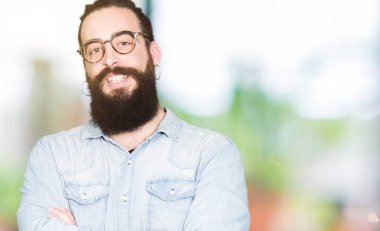 Uzun saç ve sakal ile gülümseyen bardakları mutlu yüz giyen genç hipster adamla silah kameraya bakarak geçti. Olumlu bir kişi.