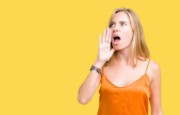 美しい若い女性が叫ぶと 口の中に手の側に大声で叫んで分離の背景にオレンジ色のシャツを着てします 通信の概念 — ストック写真