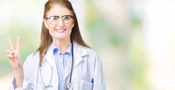 中年成熟的医生妇女穿着医疗外套在孤立的背景显示和手指第二 同时微笑着自信和快乐 — 图库照片